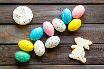 Easter background. Painted eggs and bunny on dark wooden desk top-down