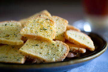 Crispy Breads in black dish and hot tea in glass all put on old wooden table