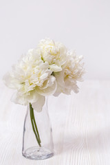 White flowers peonies in glass vase. Still life. Concept of mother, wooden, Valentines day. Soft selective focus.