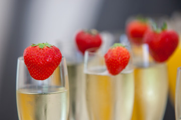 Glasses of sparkling wine or champagne and strawberry on a blurry background during some sort of festivity or celebration such as a wedding, borthday or newyear