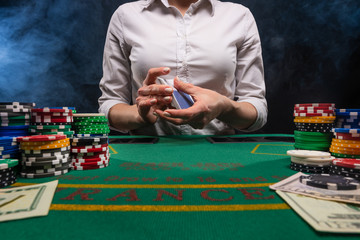 The croupier deals cards in a casino, for playing poker, against the background of the table, chips. Gaming business in Las Vegas