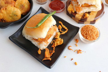 Vada pav or wada pao is a vegetarian fast food dish native to the state of Maharashtra. Famous Mumbai street food served with Red chutney and fried green chili. Copy space