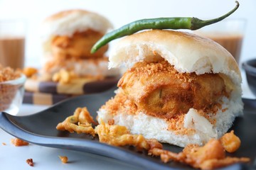 Vada pav or wada pao is a vegetarian fast food dish native to the state of Maharashtra. Famous Mumbai street food served with Red chutney and fried green chili. Copy space