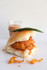 Vada pav or wada pao is a vegetarian fast food dish native to the state of Maharashtra. Famous Mumbai street food served with Red chutney and fried green chili. Copy space