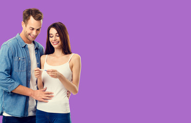 Love, relationship, new parents and happy family concept - young lovely couple, finding out results of a pregnancy test. Purple violet color background.