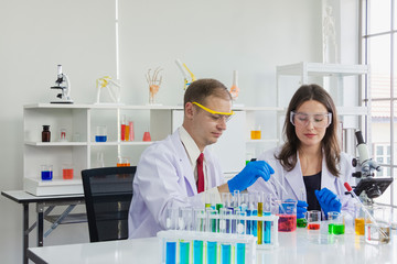 Fototapeta premium emale and male scientist ware safety glasses are doing dip chemical to beaker in laboratory
