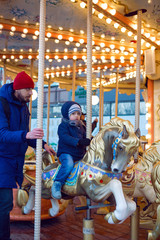 Fototapeta na wymiar son and dad ride a carousel in winter in Moscow 2020