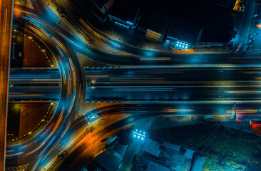Aerial top-down view of illuminated highway interchange at night, showcasing flowing traffic lights...