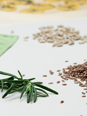 A branch of fresh rosemary, flax and sunflower seeds on the kitchen table. Close up. Herbs for making crackers.
