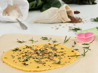 Close up, cookie dough with aromatic herbs, seeds and parmesan on a table. The process of making crackers. The concept of home cooking.