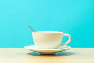white Cup with a spoon on the table, blue background