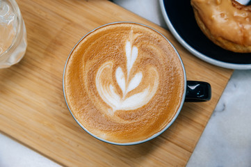 Cup with coffee and sweet tasty donut on  table.
