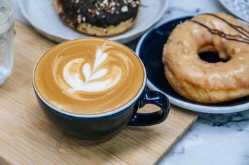 Cup with coffee and sweet tasty donut on  table.