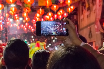 Fototapeta na wymiar Hands with cellphone recording the Chinese New Year festivities
