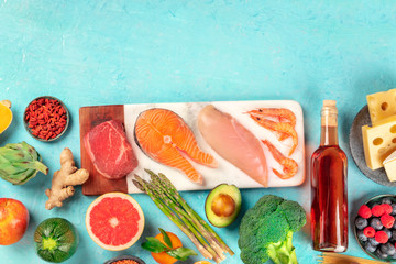 Food variety, shot from the top on a blue background with a place for text. Proteins, wine, fruit and vegetables, a design template with copy space