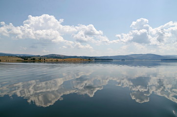 Natural reflection on Vlasina Mountain Lake and beautiful cloudy sky, Southeastern Serbia, Europe  