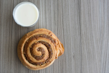 Glass of Milk and Bun on Wood Table.