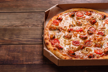 Tasty sliced pizza with seafood and tomato on a concrete background