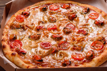 Tasty sliced pizza with seafood and tomato on a concrete background