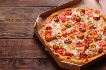 Tasty sliced pizza with seafood and tomato on a concrete background