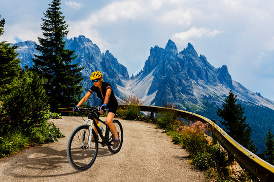 Tourist cycling in Cortina d'Ampezzo, stunning rocky mountains on the background. Woman riding MTB enduro flow trail. South Tyrol province of Italy, Dolomites. © Gorilla