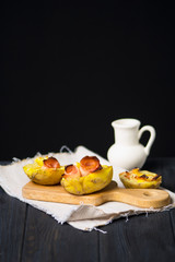 baked potatoes with cheese and ham on a dark background