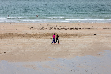 Fototapeta na wymiar Women are running along the beach in Saint-Malo, Brittany, France