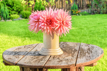 A bouquet of Dahlia flowers on an old wooden table in the yard of the house