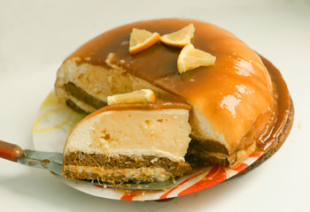 cut orange caramel mousse cake with cream cheese mascapone and chocolate glaze with nuts close up photo