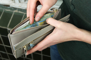Obraz premium Women's hands choose the Ukrainian hryvnia in cash wallet.
