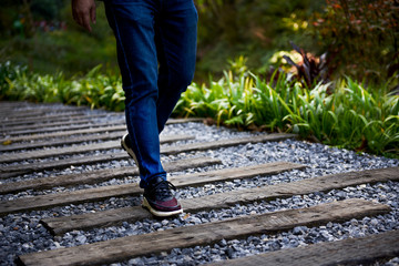 A man walks on a gravel wood path in a mountain forest