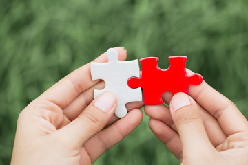 White and red jigsaw puzzles in the hands of a businessman are about to connect the pieces. Help...