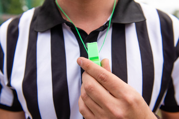 Soccer referee holds whistle at hand