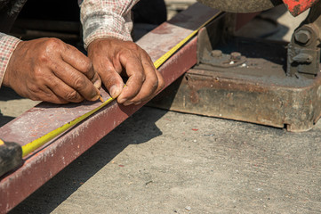 Construction worker measure metal with measure tape at construction sitebefore cutting