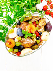 Chicken with fruits and tomatoes in pan on light board top