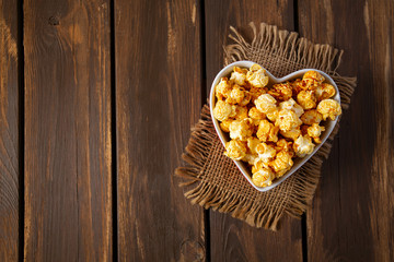 Obraz na płótnie Canvas caramelized pop corn in a heart-shaped bowl