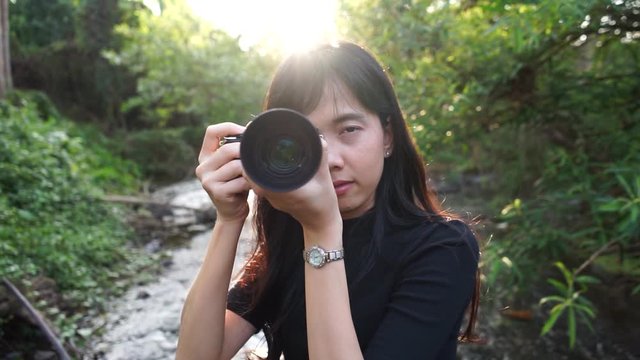 A female photographer Taking pictures on the front in the middle of nature With trees and streams
