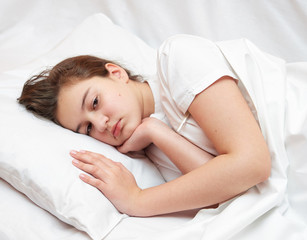 Fototapeta na wymiar sick girl lying in white bed with a thermometer. . coronavirus