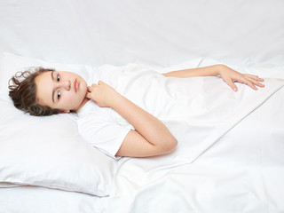 sick girl lying in white bed with a thermometer. . coronavirus