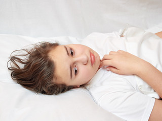 Fototapeta na wymiar sick girl lying in white bed with a thermometer. . coronavirus