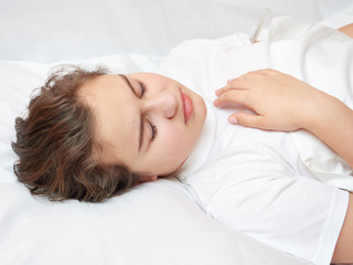 sick girl lying in white bed with a thermometer. . coronavirus