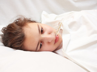 Obraz na płótnie Canvas sick girl lying in white bed with a thermometer in mouth. coronavirus