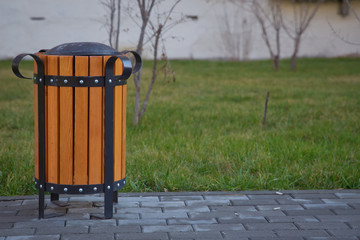 copy space on the left. Rubbish box in the park . A wooden urn and a comfortable empty park bench . Yellow garbage bin inside a wooden enclosure at a park.