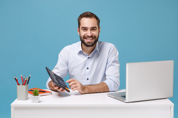 Smiling young bearded man in light shirt sit work at white desk with pc laptop isolated on pastel...