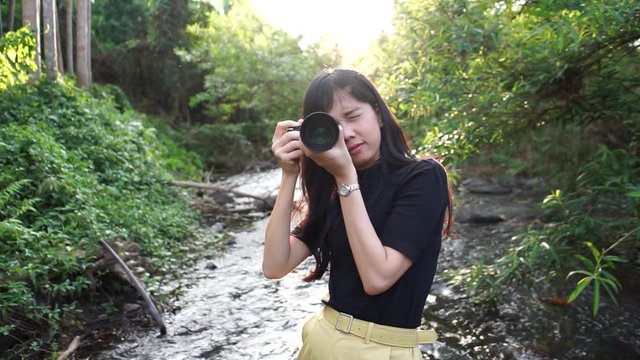A female photographer Taking pictures on the front in the middle of nature With trees and streams