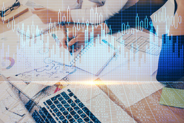 A woman hands writing information about stock market in notepad. Forex chart holograms in front. Concept of research. Double exposure
