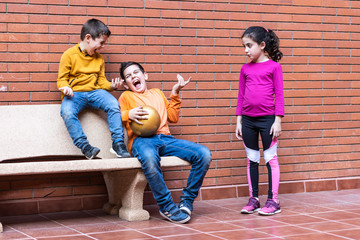 Two boys making fun of a girl because she wants to play football