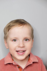 Close-up portrait of joyful baby boy. Studio shot of toddler isolated on grey background.