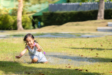 Little girl playing with splashing water at park.
