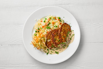 Top view of plate with liver cutlet, rice with peas and pickled cabbage